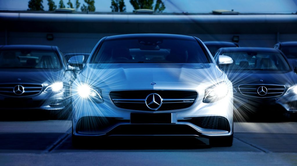 Vista frontal de una fila de automóviles Mercedes-Benz con faros brillantes, que exhiben lujo y elegancia.